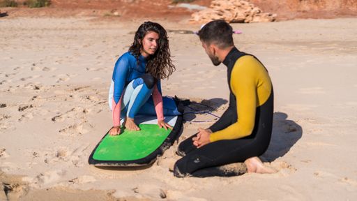 The surfer couple wearing swimsuits and preparing for surfing