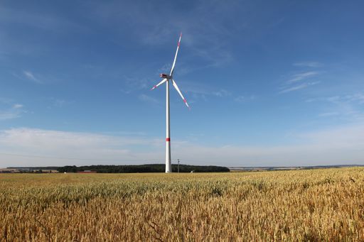 A beautiful shot of a grassland with a wind turbine under the sunlight