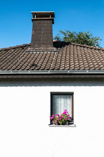 A low angle shot of a roof of a building with flowers on a window