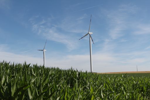 A beautiful shot of a grassland with a wind turbine under the sunlight
