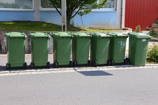 A sunny scenery of green garbage cans in the street