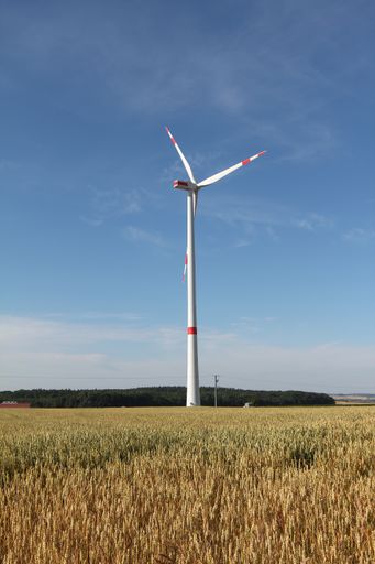 A beautiful shot of a grassland with a wind turbine under the sunlight