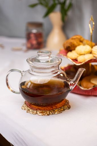 A vertical shot of glass teapot with different desserts on a table in a kitchen