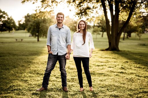 A beautiful shot of a happy couple standing in a grassy field and holding hands