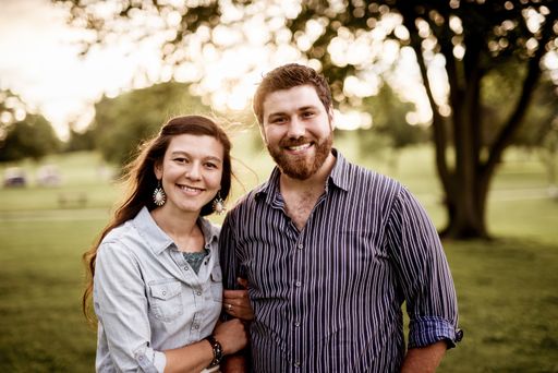 A closeup shot of a happy couple smiling while looking at the camera with a blurred background