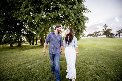 A beautiful shot of a couple walking on a grassy field while smiling at each other