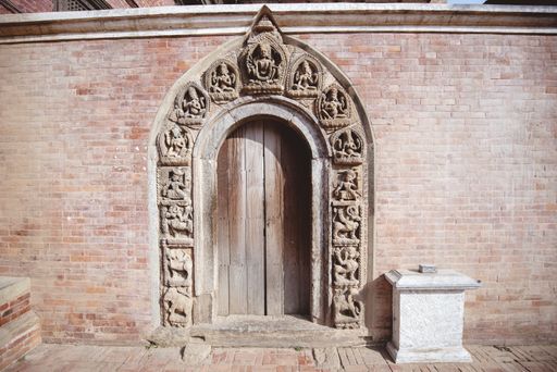A closeup shot of an arched doorway with Hindu sculptings