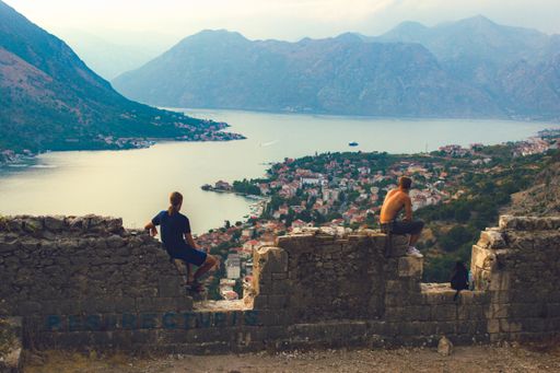 A closeup shot of men sitting on a wall enjoying the view in Kotor Fortress in Montenegro