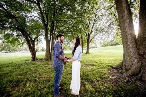 A beautiful shot of a couple standing in a grassy field while holdings hands and looking at each other