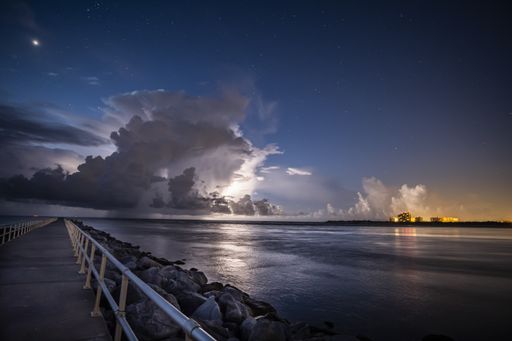 A beautiful shot of the pier and the fluffy clouds in the sky at dusk