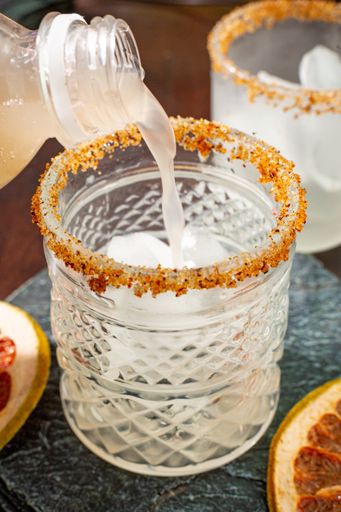 A vertical shot of a bottle pouring juice into a glass