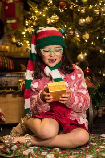 The adorable child smiling and looking at her Chrismas gift