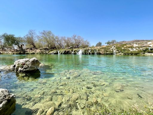 A scenic view of the waterfalls at Wadi Darbat under blue sky in Salalah, Oman