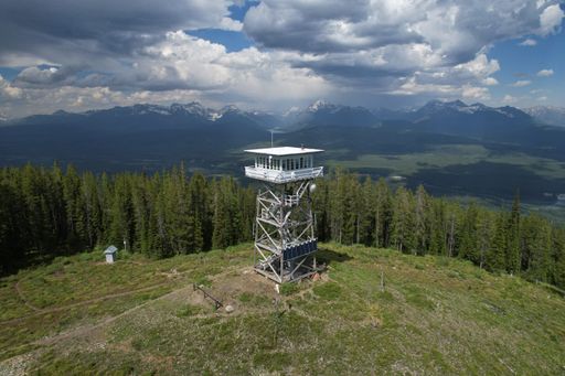 An aerial shot of Montana Fire Lookout tower with Glacier National Park wilderness behind under stormy sky