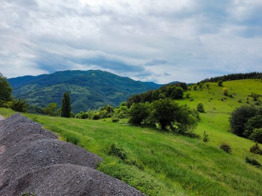 A beautiful shot of green fields and mountains against a blue cloudy sky