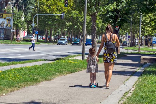 A young mother and her little girl relaxed going down the street, The girl learns to ride a scooter in Zrenjanin, Serbia