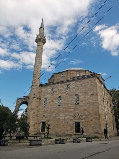 A low-angle shot of the Mosque in Prishtina against a blue clouded sky