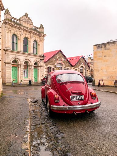 A red classic old car parked on the rainy street in Oamaru in a vertical shot