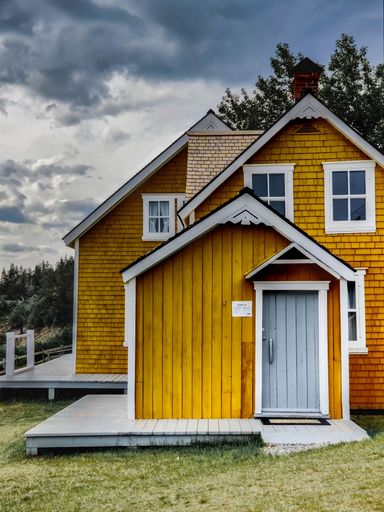 A vertical closeup of a Scandinavian wooden country house with yellow walls, gloomy sky background