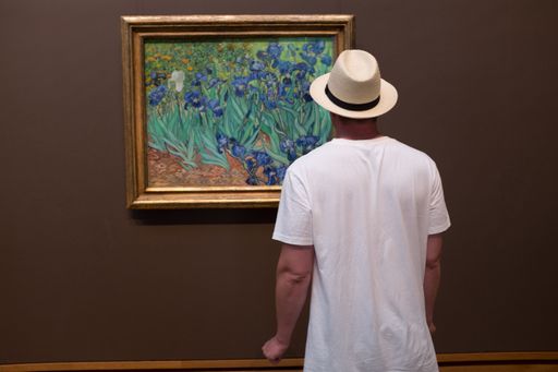 A young man with white t shirt and hat looking at painting Inside the Getty Museum in Los Angeles
