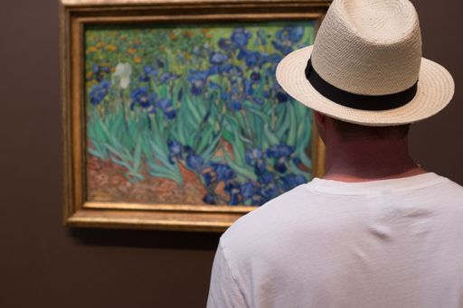 A young man with white t shirt and hat looking at painting Inside the Getty Museum in Los Angeles