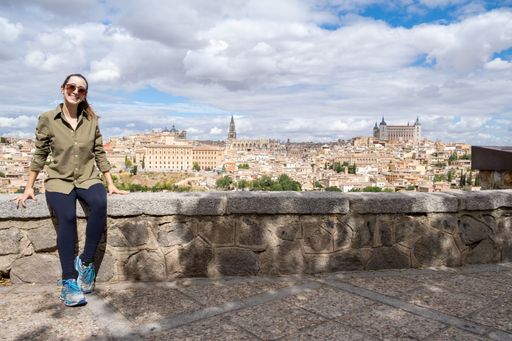 A young adult woman tourist sitting at the view looking at the city of Toledo in Spain