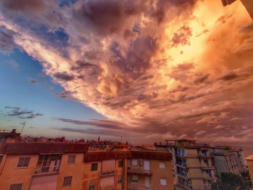 A beautiful shot of the cloudy sky at sunset with the city buildings below