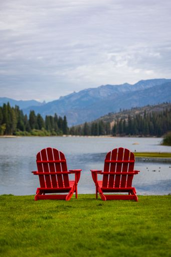 Two red chairs sitting on green grass over looking hume lake during cloudy conditions in kings canyon and sequoia national parks