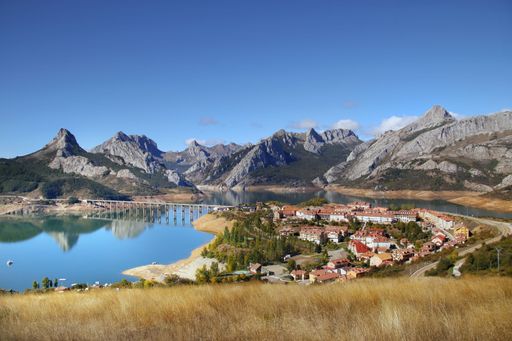 An awesome shot of a small village by the river and mountains in the background in Riano reservoir Leon Spain