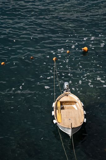 An empty wooden boat tied on the rocky coast of Vernazza, Cinque Terre, Italy