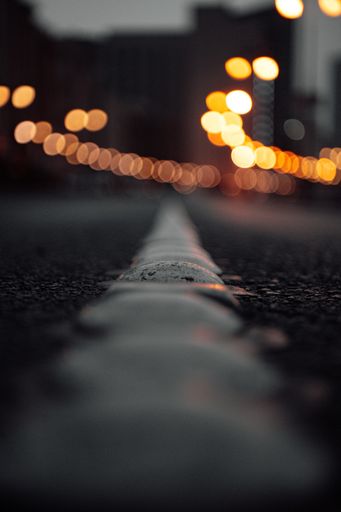 A dramatic vertical shot of an asphalt road with light bokeh