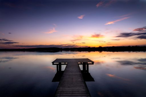 A closeup shot of a wooden bridge over lake Ammersee during an orange sunset in Germany