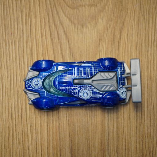 The top view of a blue Mattel Hot Wheels toy car on a wooden surface