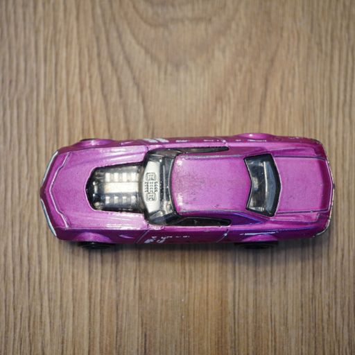 The top view of a purple Mattel Hot Wheels toy car on a wooden surface