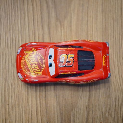 The top view of Mattel brand toy car Lighting McQueen model on a wooden surface