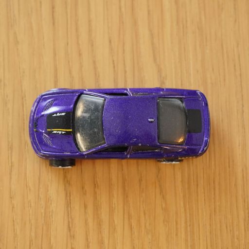The top view of a blue Mattel Hot Wheels toy car on a wooden surface