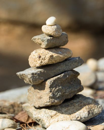 A vertical closeup shot of small stones stacked on each other with blurred background