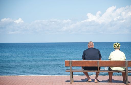 A beautiful shot of a mature couple sitting on a bench overlooking the sea