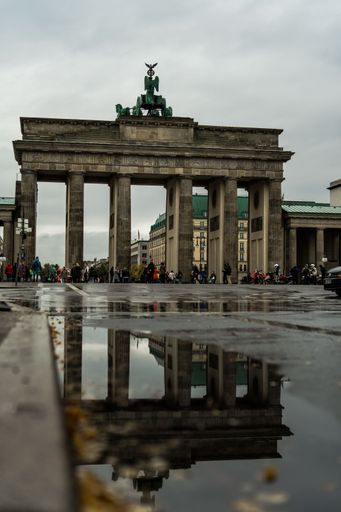 A picture of the Brandenburg Gate from the street in rainy weather. reflection in the puddle