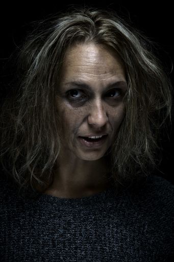 A vertical shot of an abused and scared woman on black background