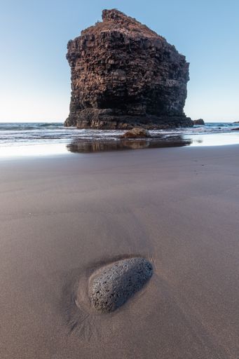 A vertical closeup shot of a huge rock formation in the sea