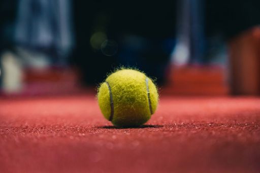 A tennis ball on the red floor with blurred background