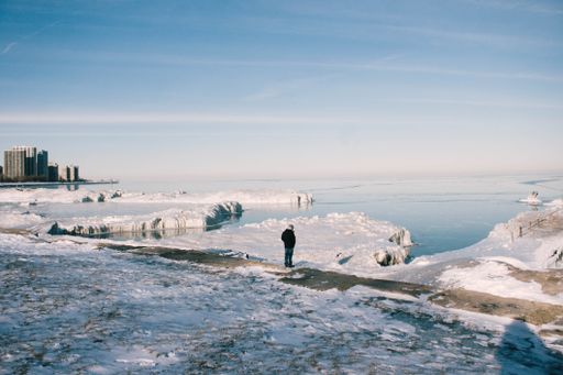 A beautiful shot of a male standing on the snowy shore of the frozen ocean on a sunny winter day