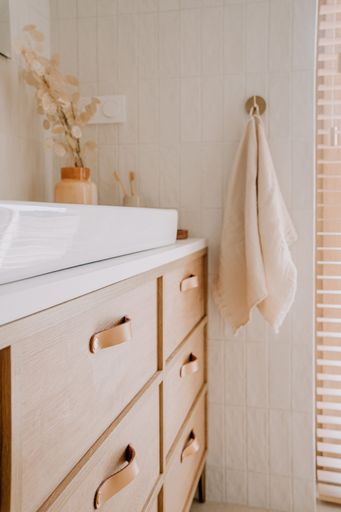 A modern bathroom features a stylish wooden vanity with ample storage and a pristine white sink
