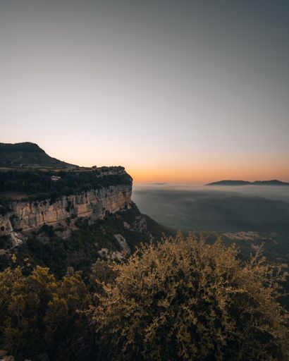 A vertical shot of a beautiful landscape of forested cliffs and misty mountains