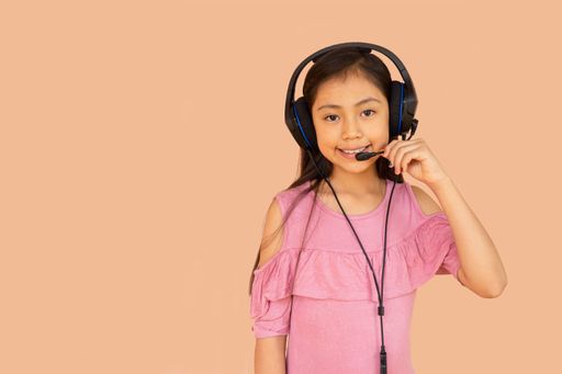 A little Hispanic girl speaking with headphones - online learning concept