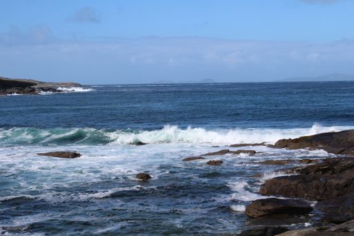 A landscape of the sea surrounded by rocks under a blue cloudy sky - perfect for wallpapers