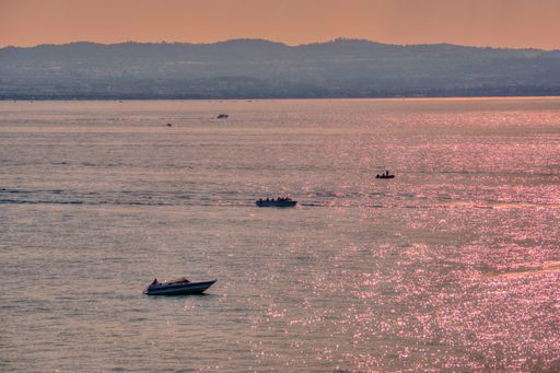 A beautiful night scenery of people driving boats during sunset in Sirmione, Italy