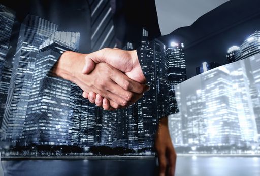 A double-exposure shot of businessmen shaking hands showing success of a deal - teamwork concept