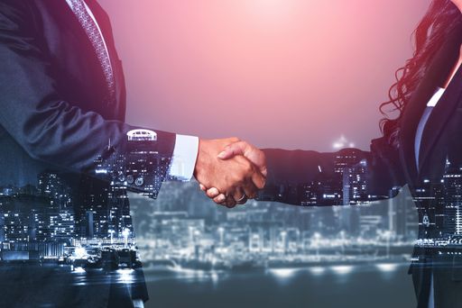A double-exposure shot of business people shaking hands showing success of a deal - teamwork concept